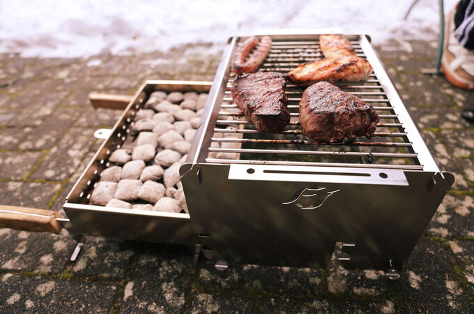 Seitenansicht des FIREJAIL ONE mit herausgezogenem Kohlebecken und Grillgut