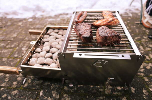 Seitenansicht des FIREJAIL ONE mit herausgezogenem Kohlebecken und Grillgut
