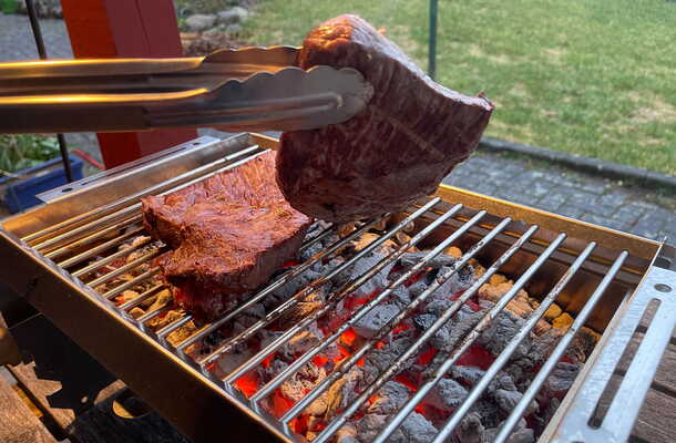 Massiver Edelstahlrost des FIREJAIL ONE mit Grillgut über glühender Kohle
